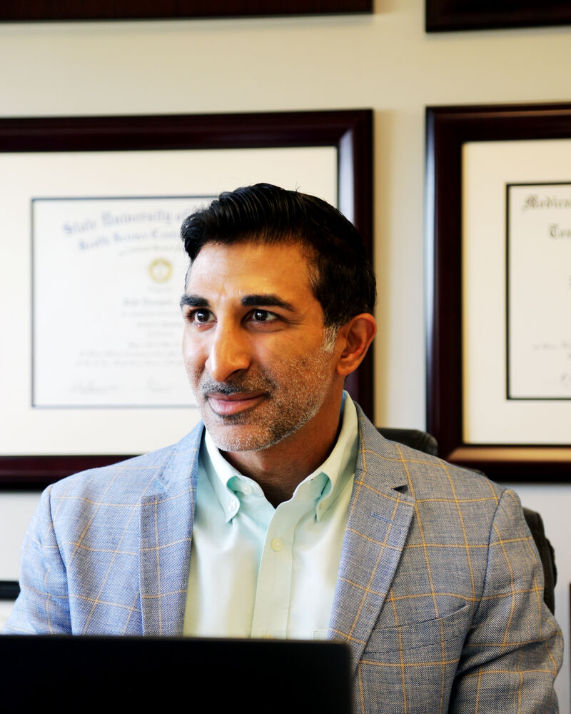 Dr. Loungani at his desk with his board certifications on the wall